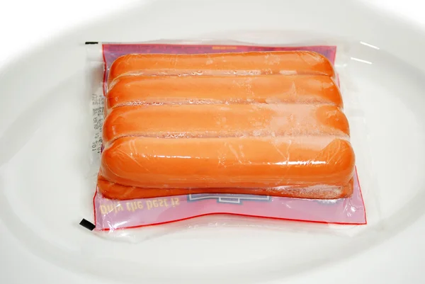 Thawing Frozen Packaged Hotdogs on a Plate — Stock Photo, Image