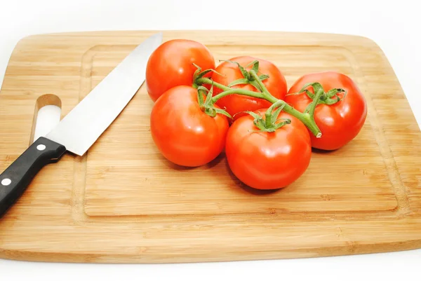 Tomates en una tabla de cortar con un cuchillo —  Fotos de Stock