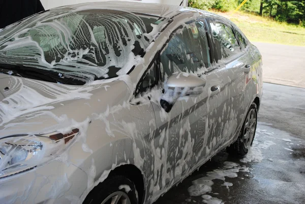 Автомобиль, покрытый мылом в стиральной комнате — стоковое фото