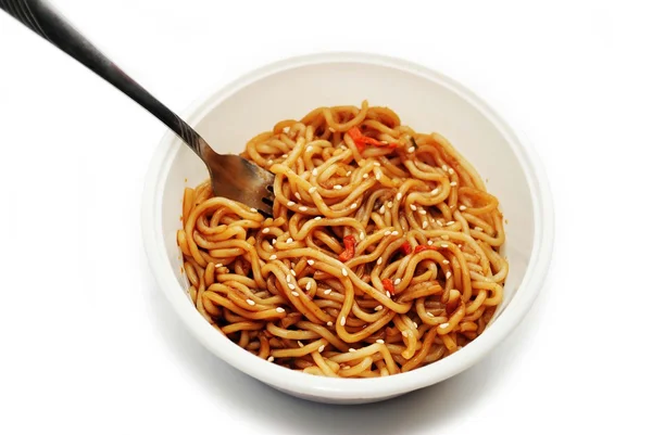 Comer fideos asiáticos con semillas de sésamo con un tenedor —  Fotos de Stock