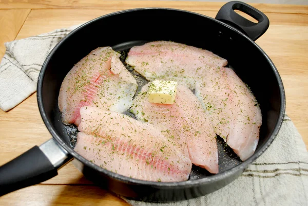 新鲜的罗非鱼在有黄油和香草的黑盘里烧烤 — 图库照片