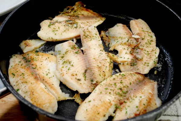 新鲜的罗非鱼在有黄油和香草的黑盘里烧烤 — 图库照片
