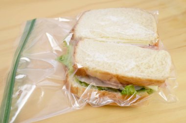 Okula götürmek ya da öğle yemeği için çalışmak için plastik poşette jambonlu sandviç.
