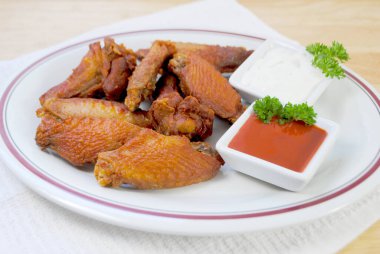 Baharatlı ve Kızarmış Bufalo Kanatları Acı sos ve Mavi Peynir Sosu ile servis edilir.