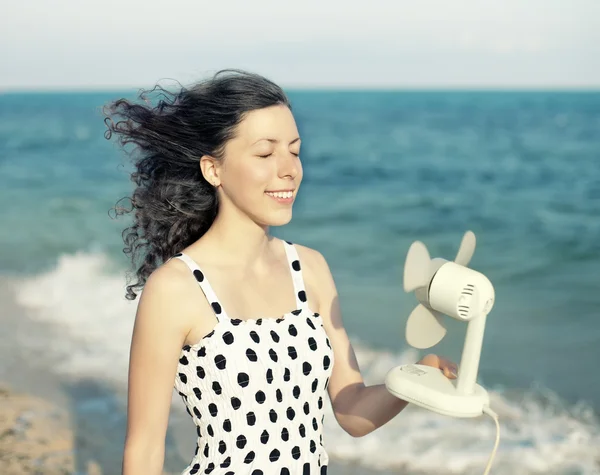 Mädchen kühlt sich am Strand mit einem Ventilator ab — Stockfoto