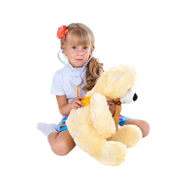 Menina brincando médico com brinquedo urso isolado no fundo branco — Fotografia de Stock