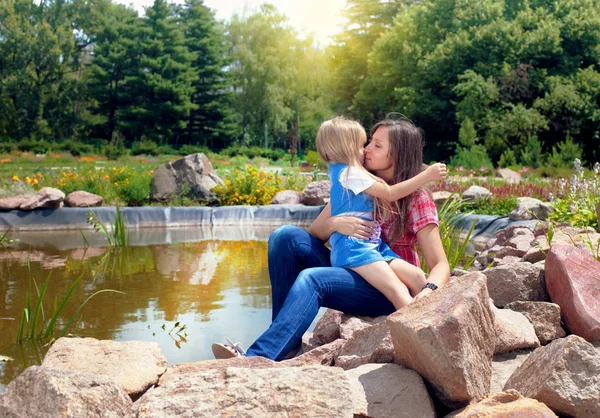 Happy mother and daughter hugging near pond — Stock Photo, Image