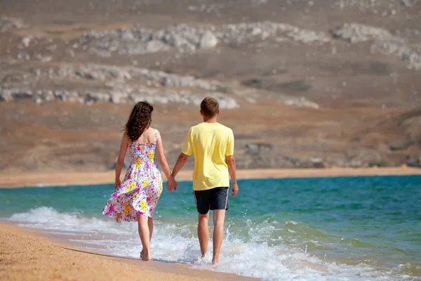 Jovem casal de mãos dadas e andando despreocupado na praia em férias de verão — Fotografia de Stock