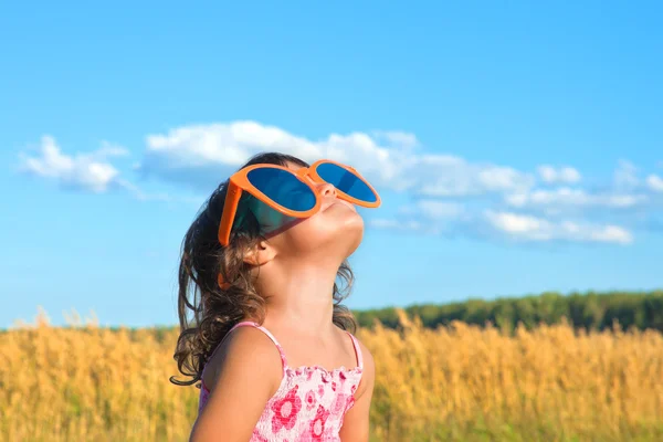 Niña feliz con grandes gafas de sol mirando al cielo —  Fotos de Stock