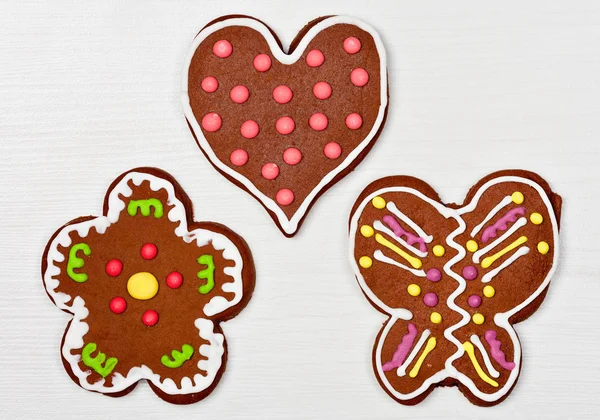 Biscuits en forme de coeur, de fleur et de papillon sur une surface en bois blanc — Photo