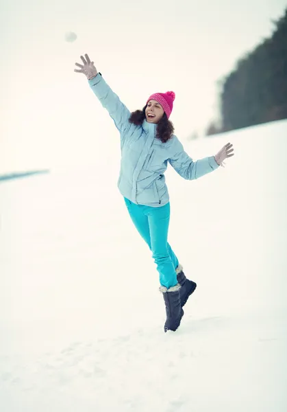 Happy young woman throwing snowball on the snowy field — Stock Photo, Image