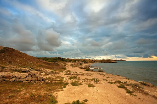 Puesta de sol sobre una costa rocosa — Foto de Stock