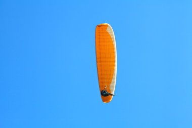 Mavi gökyüzünde süzülen paraglider