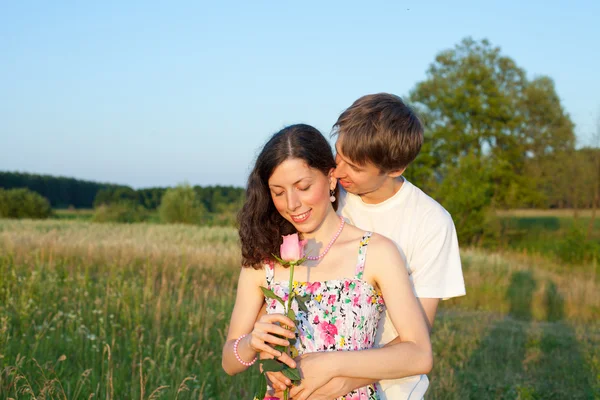 Liefdevolle jonge man zijn vriendin met roos knuffelen in haar handen — Stockfoto