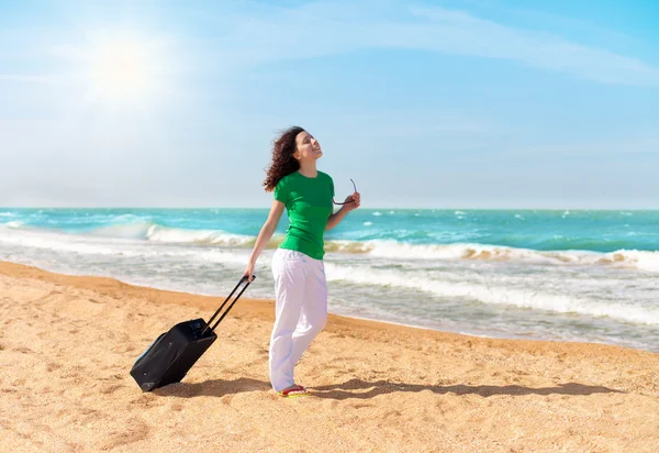 Glad flicka med resa påse promenerar på stranden — Stockfoto