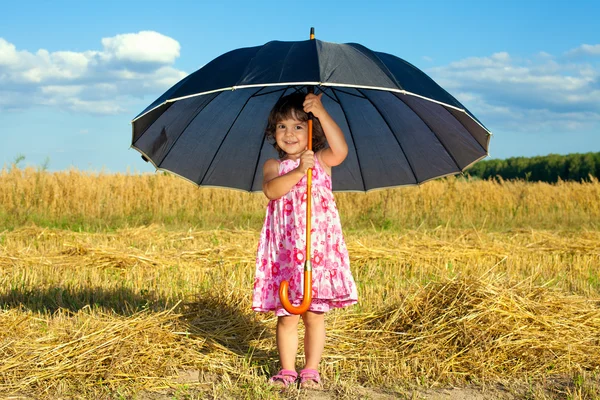 Felice bambina nascosta sotto grande ombrello nero nel bel tempo — Foto Stock