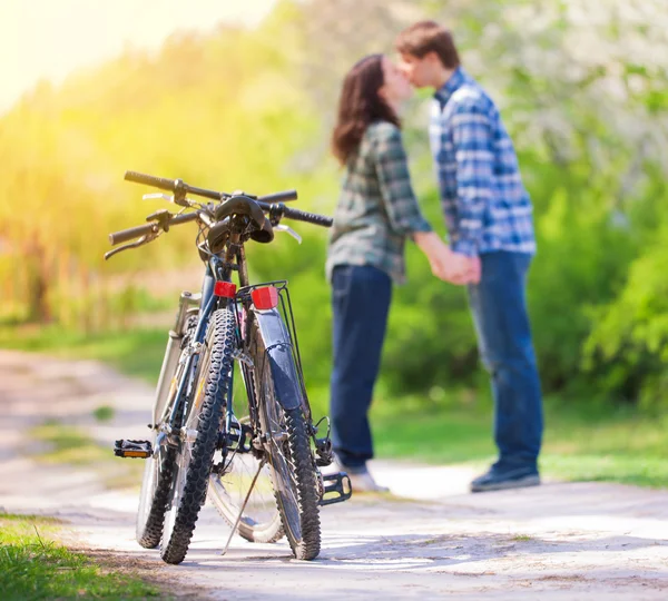 Two bicycles in front of young kissing couple — Stock Photo, Image