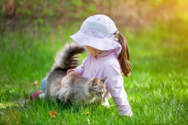 çimenlerin üzerinde kedi ile oynarken kız
