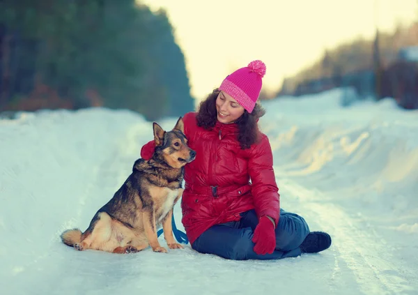 Jovem mulher abraçando cão na tempestade de neve — Fotografia de Stock