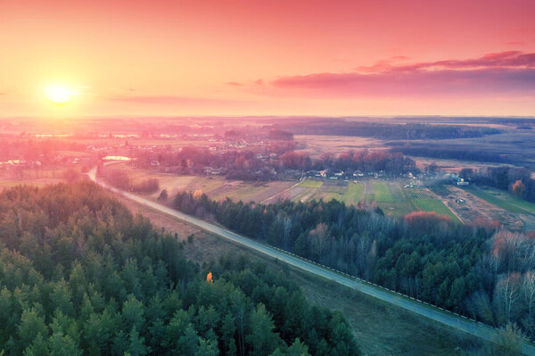 Aerial view of the rural landscape with a country road. The countryside landscape in the spring evening.