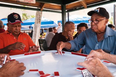 Miami, Florida ABD - 18 Haziran 2022: Popüler Little Havana 'daki tarihi Domino Parkı' nda kimliği belirsiz yaşlılar domino oyunu oynuyorlar.