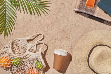 Yaz güneşi konsepti düz katlı. Şapka, meyve dolu ip torbası, bardak, palmiye yaprağı..