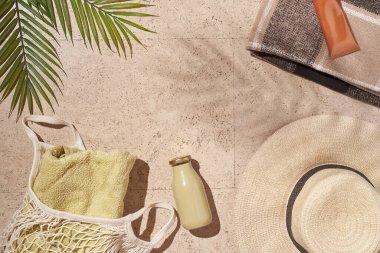 Yaz güneşi konsepti düz katlı. Şapka, havlu ve şişeli ip torbası, yapraklar.