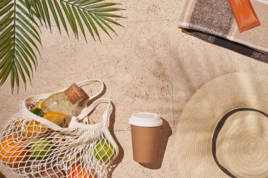 Yaz güneşi konsepti düz katlı. Şapka, meyve dolu ip torbası, bardak, palmiye yaprağı..