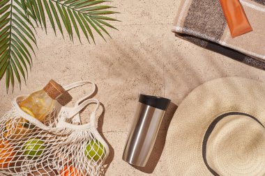 Yaz güneşi konsepti düz katlı. Şapka, meyve dolu ip torbası, bardak, palmiye yaprağı..