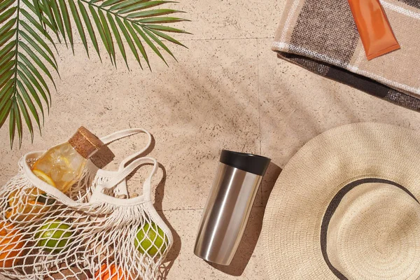 Yaz güneşi konsepti düz katlı. Şapka, meyve dolu ip torbası, bardak, palmiye yaprağı..