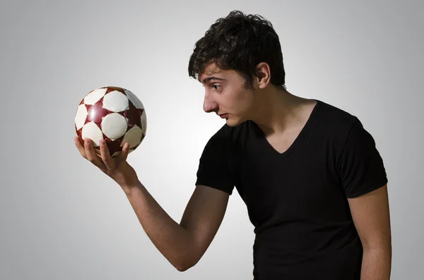 Jeune homme joue Hameau avec un petit ballon de football Image En Vente
