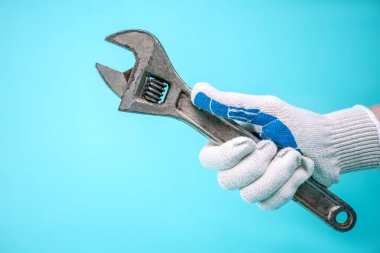 Eldivenli bir adamın eli İngiliz anahtarını tutar..