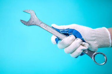 Eldivenli bir adamın eli İngiliz anahtarını tutar..