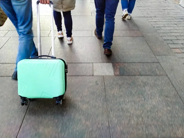 A man with a small green suitcase walks to the train station. Coronavirus pandemic travel concept