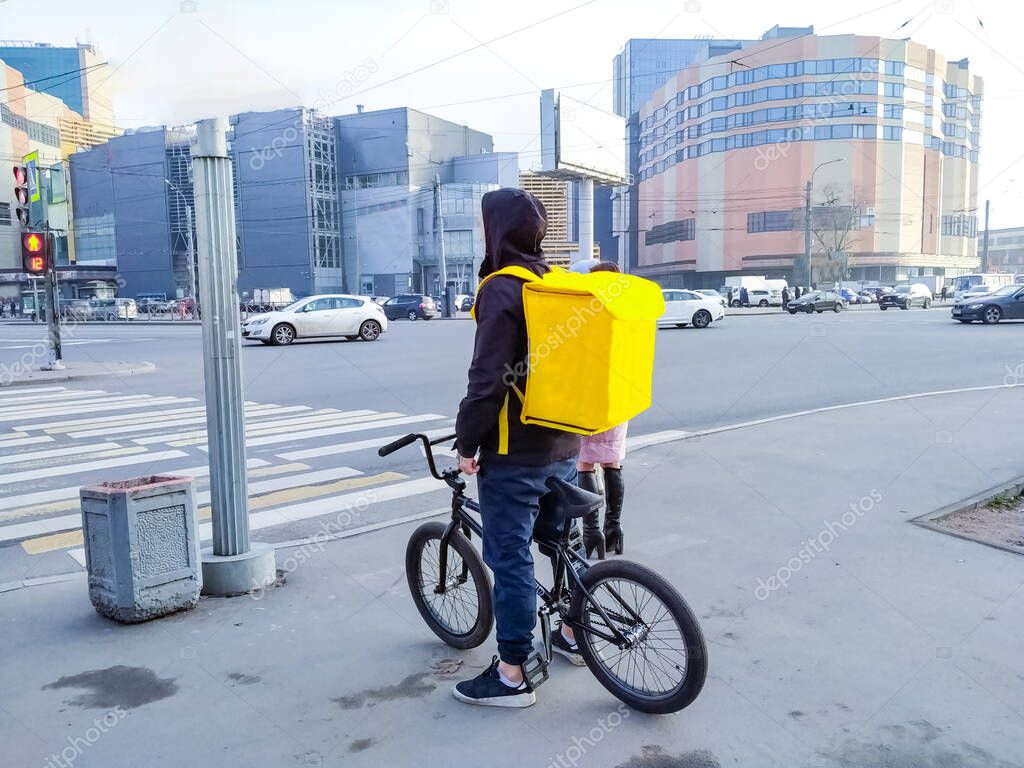 Courier with a yellow backpack in the city carrying food
