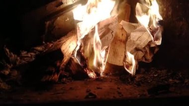 Bir adam şöminede odunla kağıt yakıyor. Evde soğuk havada ısıtma metodu