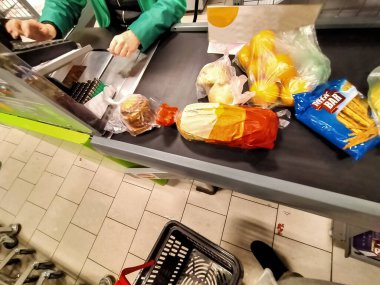 Dükkandaki kasanın önünde bir adam ürünleri koydu ve kasiyerin ödeme yapmasını bekledi.