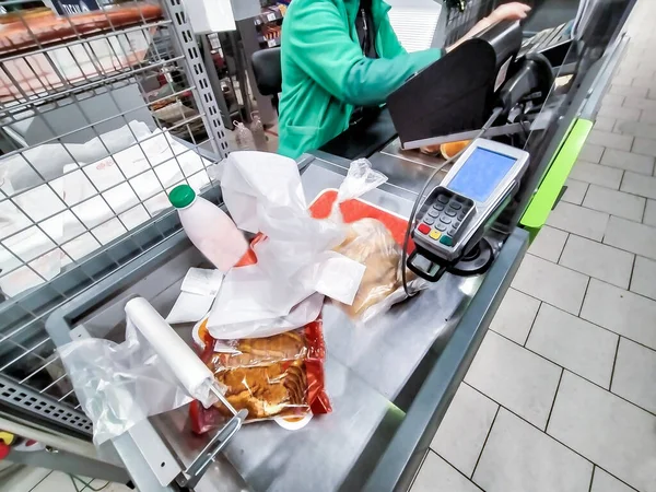 Marketteki kasanın önündeki adam malların parasını ödedi.