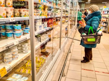 12 Ocak 2022 'de St. Petersburg Rusya' da yaşlı bir kadın kışın manavda süt ürünleri seçiyor. Yazı