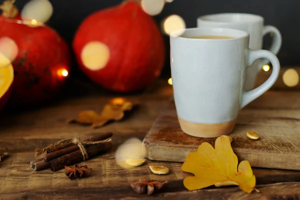 Pumpkin spiced coffee in ceramic cups on a wooden table with orange pumpkins in the background. Bokeh. Autumn mood. Time to drink hot beverage.