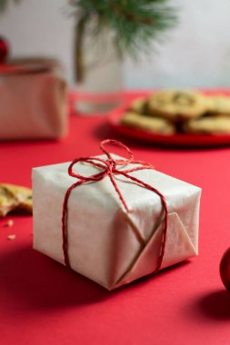 Küçük bir yeni yıl hediyesi el sanatları kağıdına doldurulur, bir tabak kurabiye ve masada bir bardak süt, köknar dallı bir vazo. Seçici odaklanma. Noel havası.