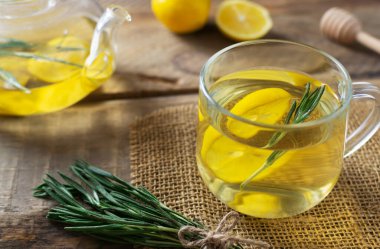 Biberiyeli, limonlu ve ballı bir fincan sıcak çay ve ahşap bir masada bir çaydanlık. Kırsal tarzda. Alternatif tıp konsepti. Yatay oryantasyon. Seçici odak.