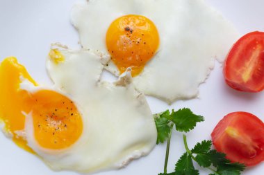 İki sahanda yumurta, beyaz tabakta domates ve otlar. Çirkin yemek konsepti. Üst Manzara. Çirkin yemeğin tadı güzel yemekle aynı..