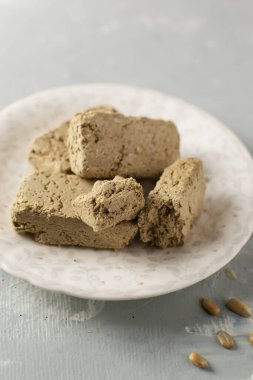 Beyaz bir tabağın üzerinde birkaç parça ayçiçeği halkası ve gri arka planda tohumlar. Geleneksel doğu tatlıları kavramı. Dikey yönelim.