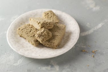 Beyaz bir tabağın üzerinde birkaç parça ayçiçeği halkası ve gri arka planda tohumlar. Geleneksel doğu tatlıları kavramı. Yatay oryantasyon. Boşluğu kopyala.