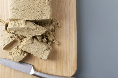 Parçalanmış ayçiçeği halkası gri bir arka planda tahta kesme tahtasının üzerinde metal bir bıçakla yatar. Geleneksel doğu tatlıları kavramı. Yatay oryantasyon. Uzayı kopyala Üst görünüm.