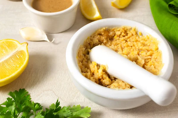 Mix the boiled chickpeas and garlic with lemon juice thoroughly in a ceramic mortar. Ingredients for making hummus. Boiled chickpeas, tahini, garlic, lemon and butter. Step by step.