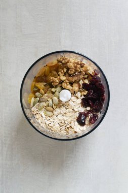 Evde enerji çikolatası yapma süreci. Yulaf ezmesi, kızılcık, kuru üzüm, kabak çekirdeği, fındık. Kuru malzemeler karıştırmak için miksere konur. Sağlıklı gıda konsepti. Üst görünüm.