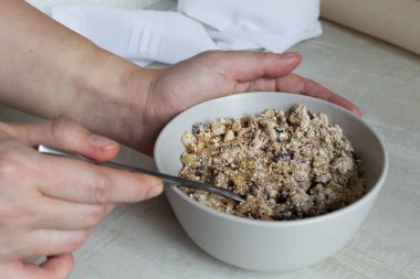 Evde enerji çikolatası yapma süreci. Bal içeriğe eklenir ve iyice karıştırılır. Kadın eli kaşıkla hamuru karıştırır. Sağlıklı gıda konsepti.