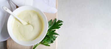 Tahta kesme tahtasındaki beyaz bir kasede maydanozlu ev yapımı mayonez. Düzgün beslenme kavramı. Yatay oryantasyon. Pankart. Boşluğu kopyala.